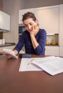 Unemployed and divorced woman with debts reviewing her monthly bills